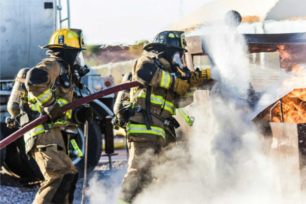 two fire fighters spraying a water hose into a vehicle fire 600x400